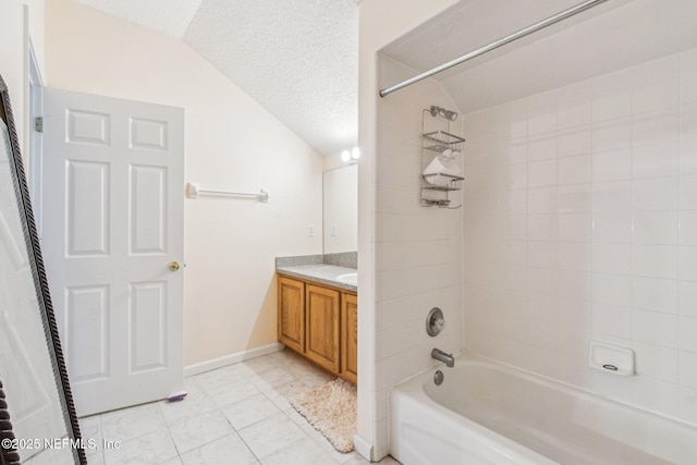 bathroom featuring vanity, a textured ceiling, vaulted ceiling, tile patterned floors, and tiled shower / bath