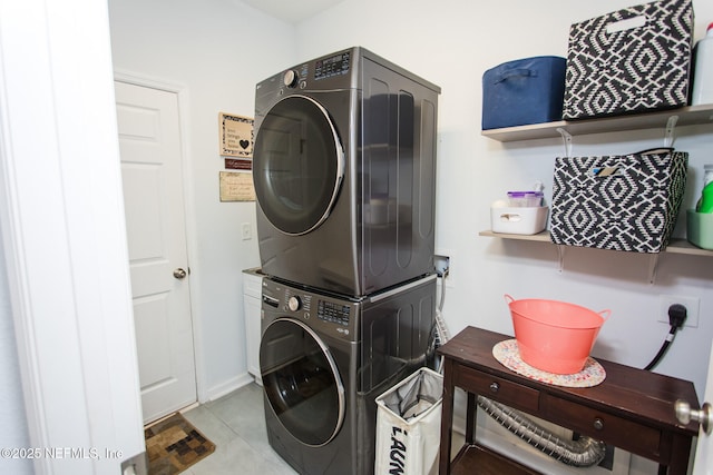 laundry area with stacked washer / drying machine and light tile patterned floors