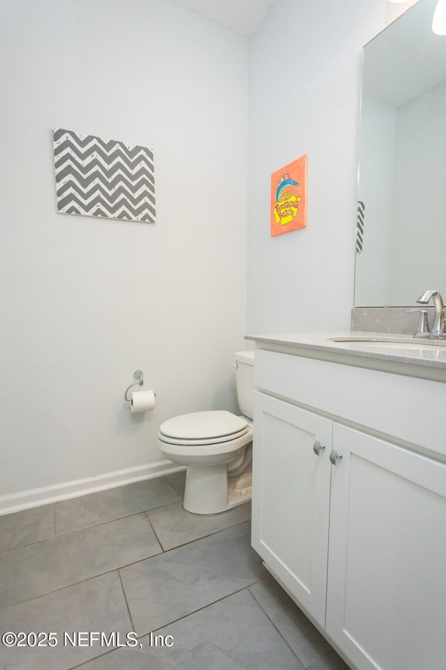 bathroom with toilet, vanity, and tile patterned floors