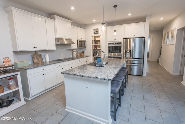 kitchen with white cabinets, appliances with stainless steel finishes, a kitchen island with sink, and sink