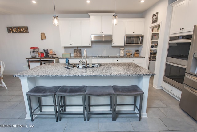 kitchen featuring a center island with sink, white cabinetry, and hanging light fixtures