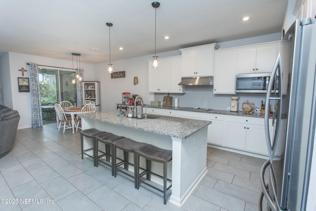 kitchen with appliances with stainless steel finishes, a kitchen breakfast bar, a kitchen island with sink, decorative light fixtures, and white cabinetry