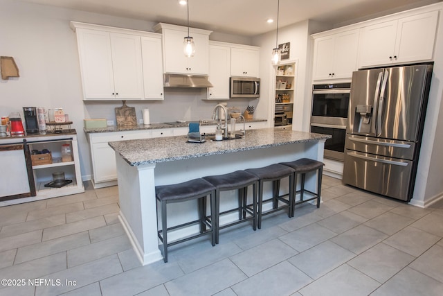 kitchen featuring stainless steel appliances, white cabinetry, hanging light fixtures, and a center island with sink