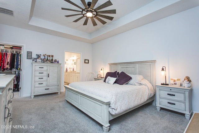 bedroom with a raised ceiling, ceiling fan, a spacious closet, connected bathroom, and a closet