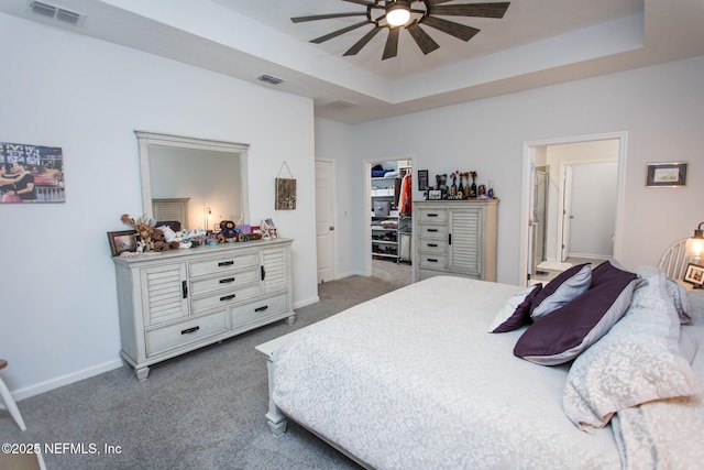 carpeted bedroom featuring a closet, a tray ceiling, and ceiling fan