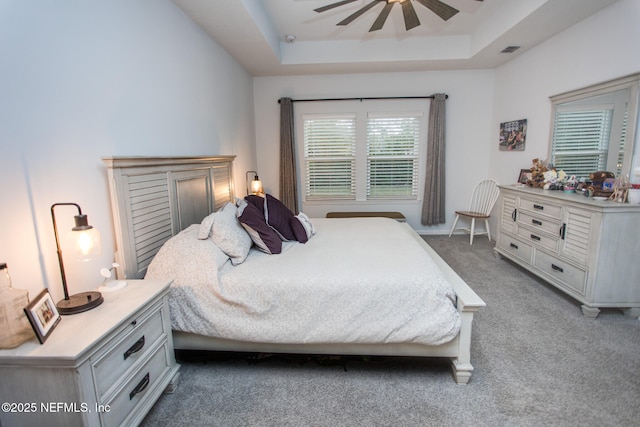 bedroom featuring a tray ceiling, ceiling fan, and light carpet