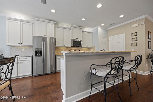 kitchen featuring light stone countertops, a center island with sink, white cabinets, and stainless steel appliances