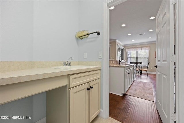 bathroom with crown molding, sink, and hardwood / wood-style flooring