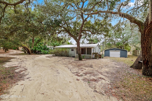 view of yard with a garage, an outdoor structure, and a sunroom