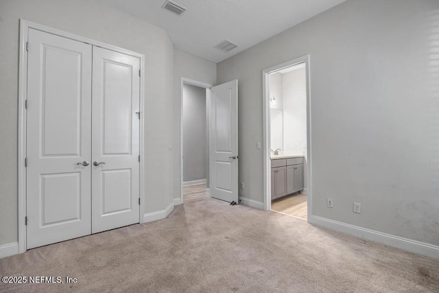 unfurnished bedroom with a closet, connected bathroom, and light carpet