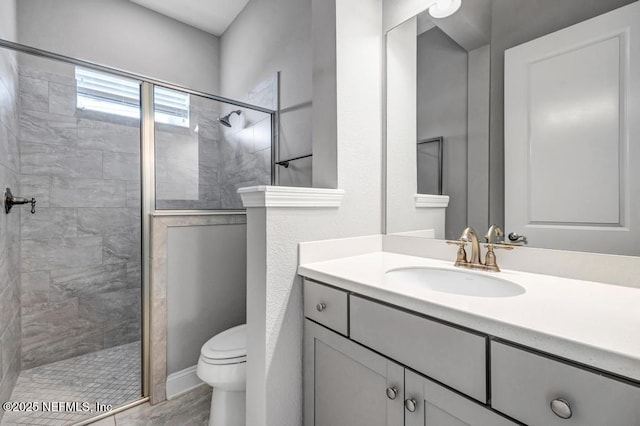 bathroom with a tile shower, vanity, and toilet