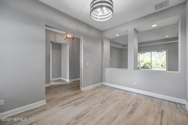 spare room featuring light hardwood / wood-style floors and a notable chandelier