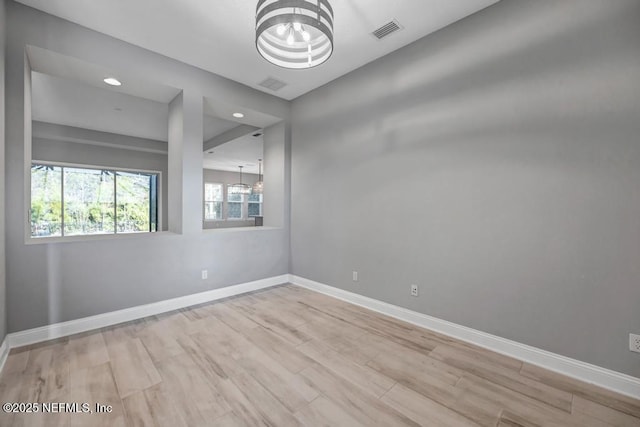 spare room featuring light hardwood / wood-style floors and a chandelier