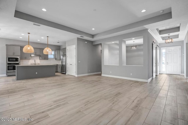 unfurnished living room with a raised ceiling and sink