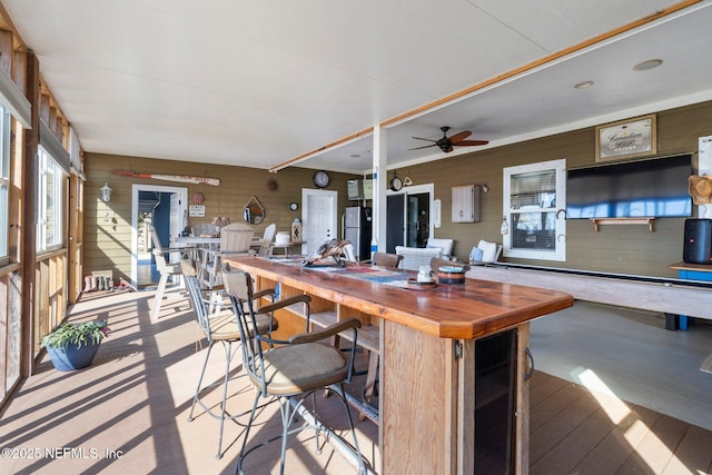 interior space featuring stainless steel fridge, ceiling fan, wooden counters, and wood walls