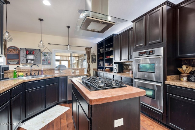 kitchen featuring sink, a center island, light hardwood / wood-style flooring, pendant lighting, and appliances with stainless steel finishes