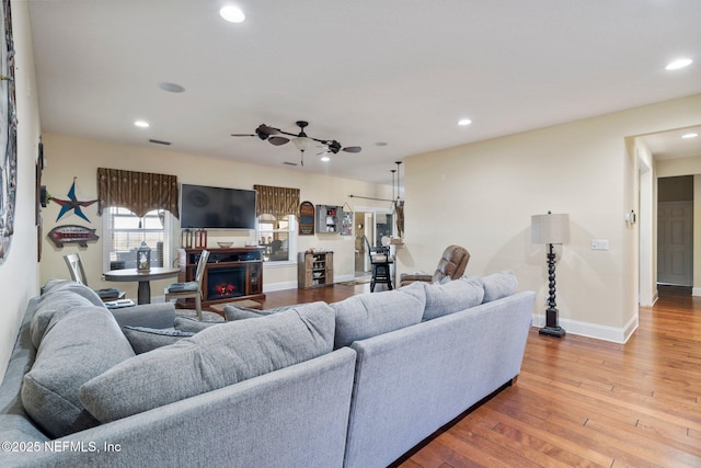 living room with hardwood / wood-style flooring, ceiling fan, and a fireplace