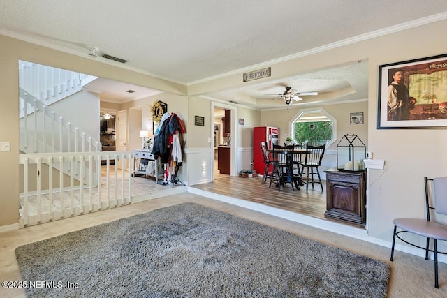 foyer entrance featuring crown molding, ceiling fan, a textured ceiling, and a tray ceiling