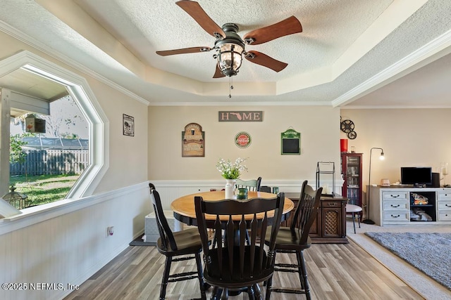 dining space with crown molding, a tray ceiling, and light hardwood / wood-style floors