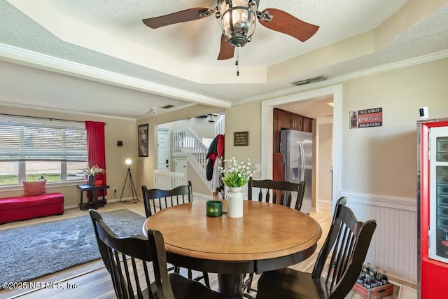 dining area with ceiling fan, a tray ceiling, ornamental molding, and a textured ceiling