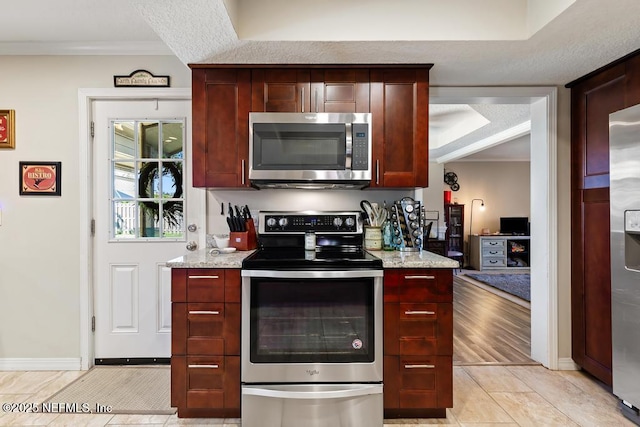 kitchen with crown molding, appliances with stainless steel finishes, light tile patterned floors, and light stone counters