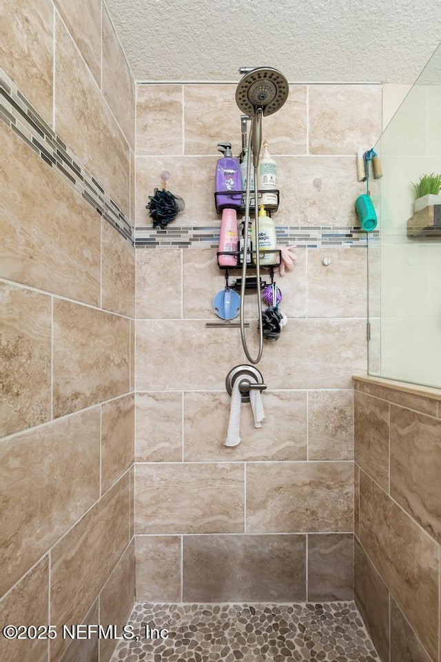 bathroom with a textured ceiling and a tile shower