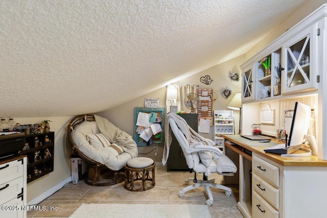 office featuring light tile patterned flooring, vaulted ceiling, and a textured ceiling