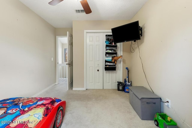 bedroom with light colored carpet, ceiling fan, and a closet