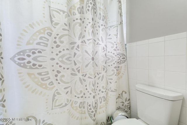 bathroom featuring toilet and tile walls