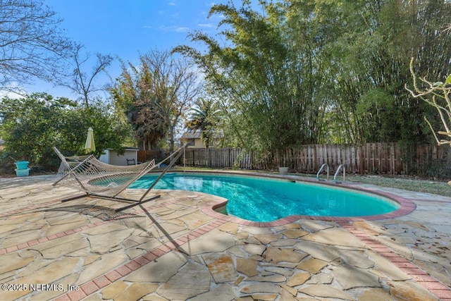 view of swimming pool featuring a shed and a patio area