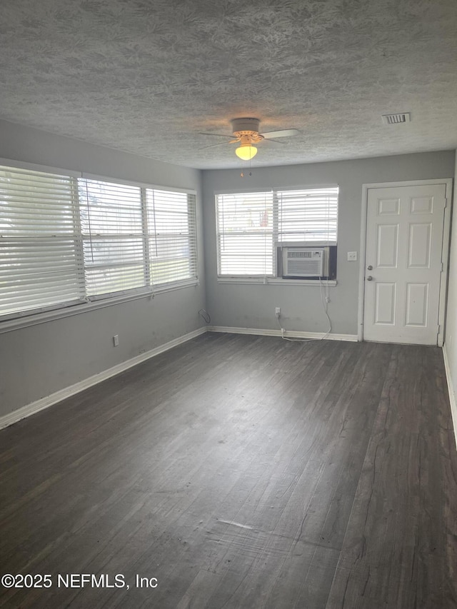 spare room with ceiling fan, dark hardwood / wood-style flooring, cooling unit, and a textured ceiling