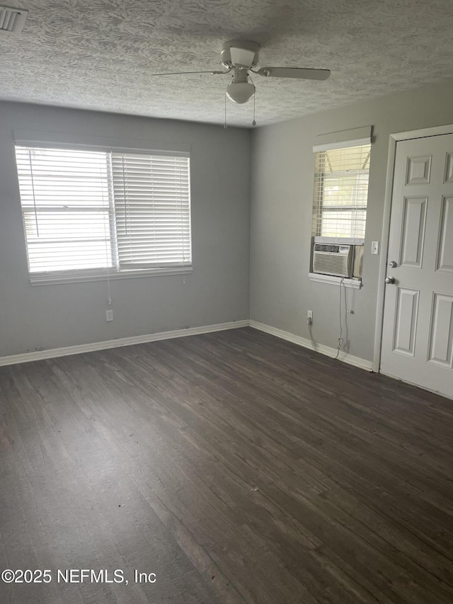 empty room featuring ceiling fan, cooling unit, dark wood-type flooring, and a textured ceiling