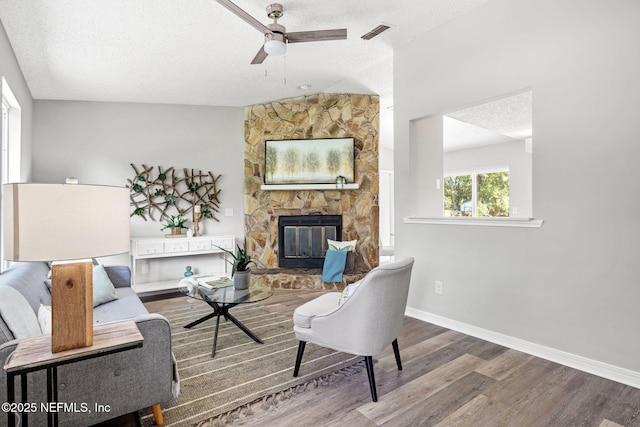 living room featuring hardwood / wood-style floors, a fireplace, ceiling fan, and a textured ceiling