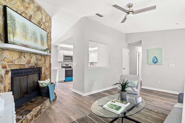 living room with a textured ceiling, ceiling fan, wood-type flooring, and vaulted ceiling