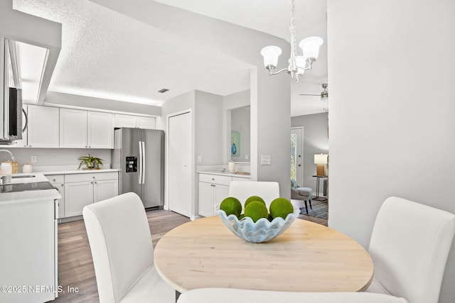 dining space featuring a chandelier, sink, light hardwood / wood-style floors, and a textured ceiling