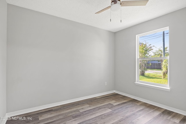 empty room with ceiling fan, wood-type flooring, and a textured ceiling