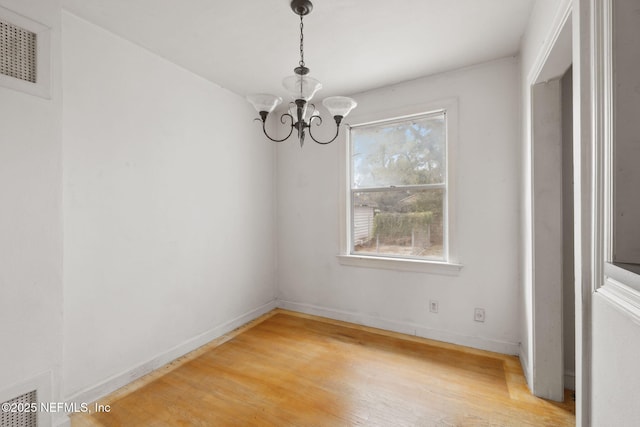 unfurnished dining area featuring hardwood / wood-style flooring and an inviting chandelier