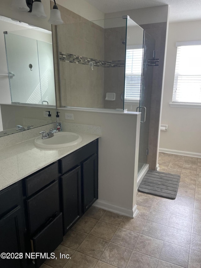 bathroom with walk in shower, vanity, and plenty of natural light