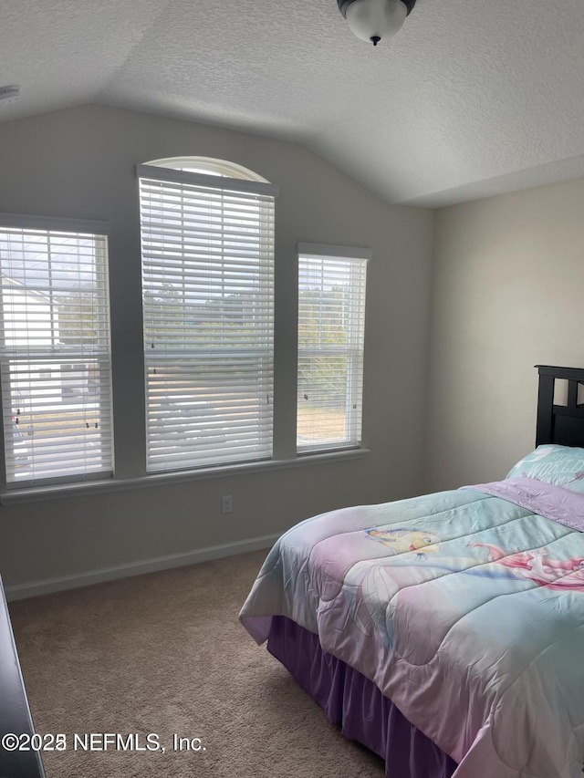 bedroom with a textured ceiling, multiple windows, lofted ceiling, and carpet flooring