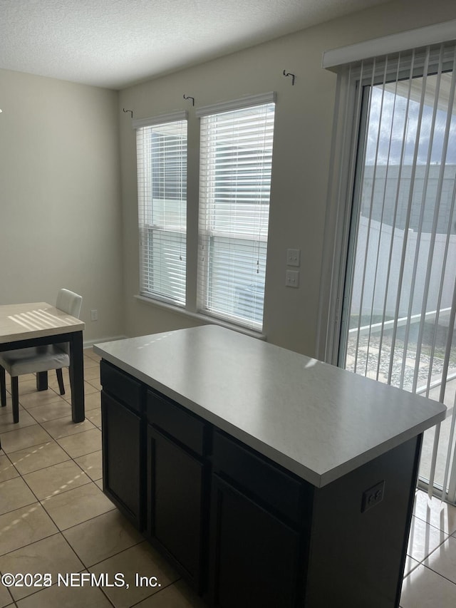 kitchen featuring light tile patterned flooring, a textured ceiling, and a center island