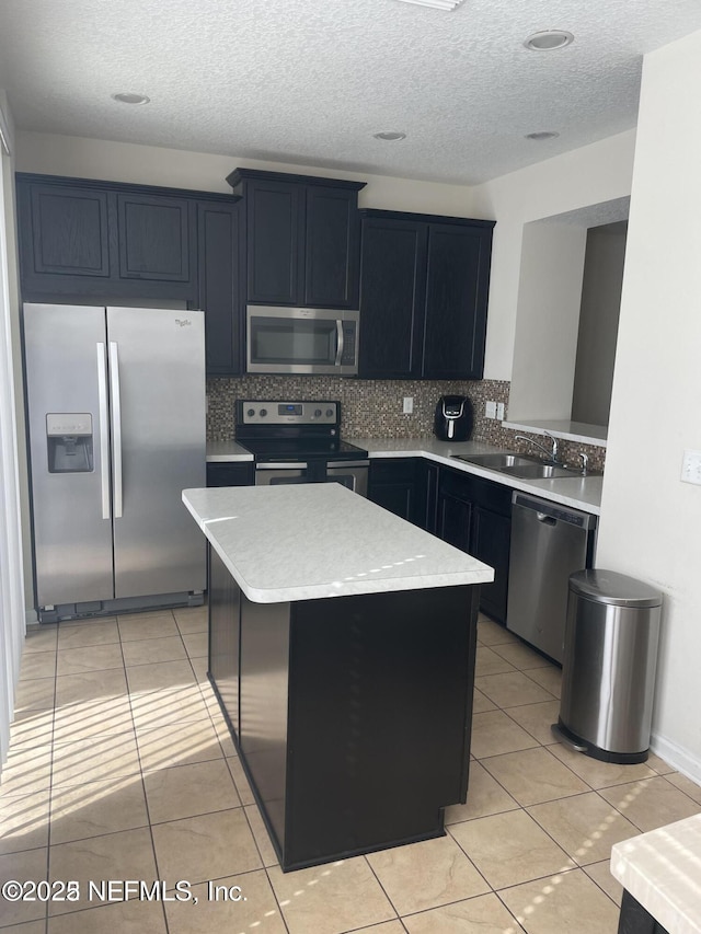 kitchen with light tile patterned floors, appliances with stainless steel finishes, tasteful backsplash, a center island, and sink