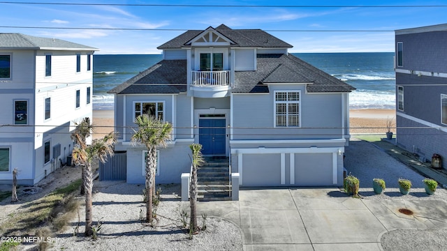 view of front of home with a balcony, a view of the beach, a garage, and a water view