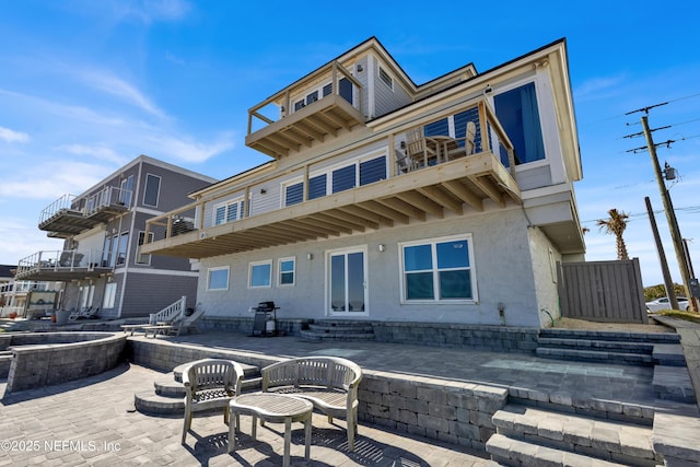 rear view of property with a balcony and a patio area