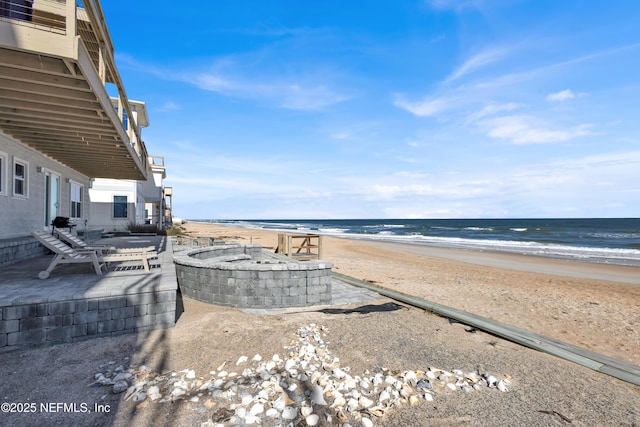 view of water feature featuring an outdoor fire pit and a beach view