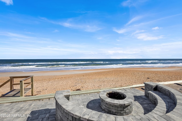 water view with a fire pit and a view of the beach