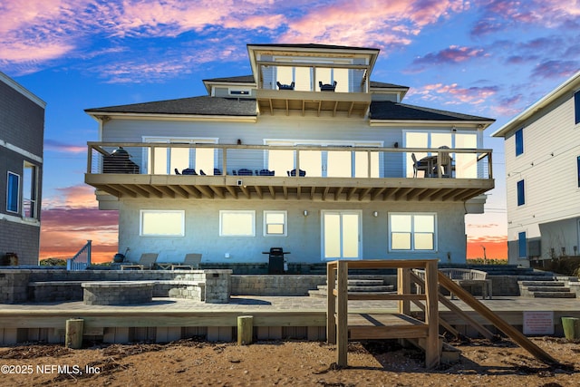 back house at dusk featuring a balcony