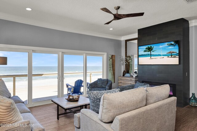 living room with a fireplace, ornamental molding, hardwood / wood-style flooring, and a water view