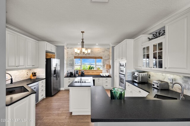 kitchen with a notable chandelier, stainless steel appliances, crown molding, and sink