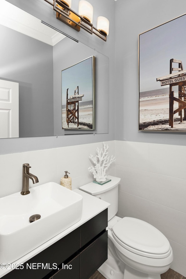 bathroom with toilet, vanity, tile walls, and crown molding