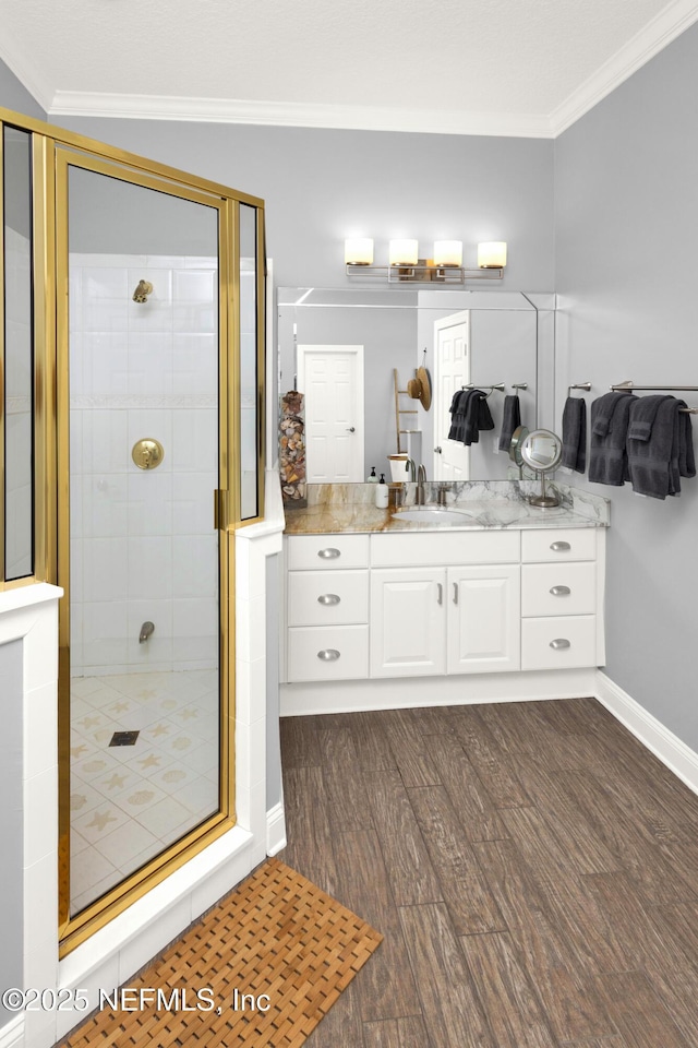 bathroom with hardwood / wood-style floors, a shower with shower door, crown molding, and vanity